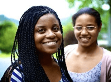 Two young women standing and smiling towards the camera.